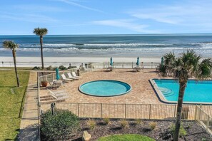 A pool area with a view of the beach and ocean.