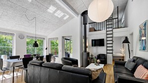 Ein modernes Wohnzimmer mit Kamin, Essbereich und einer Treppe zu einer oberen Ebene.