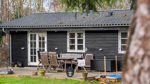 A log cabin with a deck, outdoor seating, and a blue trampoline. - Stunning home in Holbæk with sauna (Holbæk)