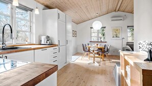 A modern kitchen with white cabinets, a wooden countertop, and a dining area with a table and chairs. - Stunning home in Holbæk with sauna (Holbæk)