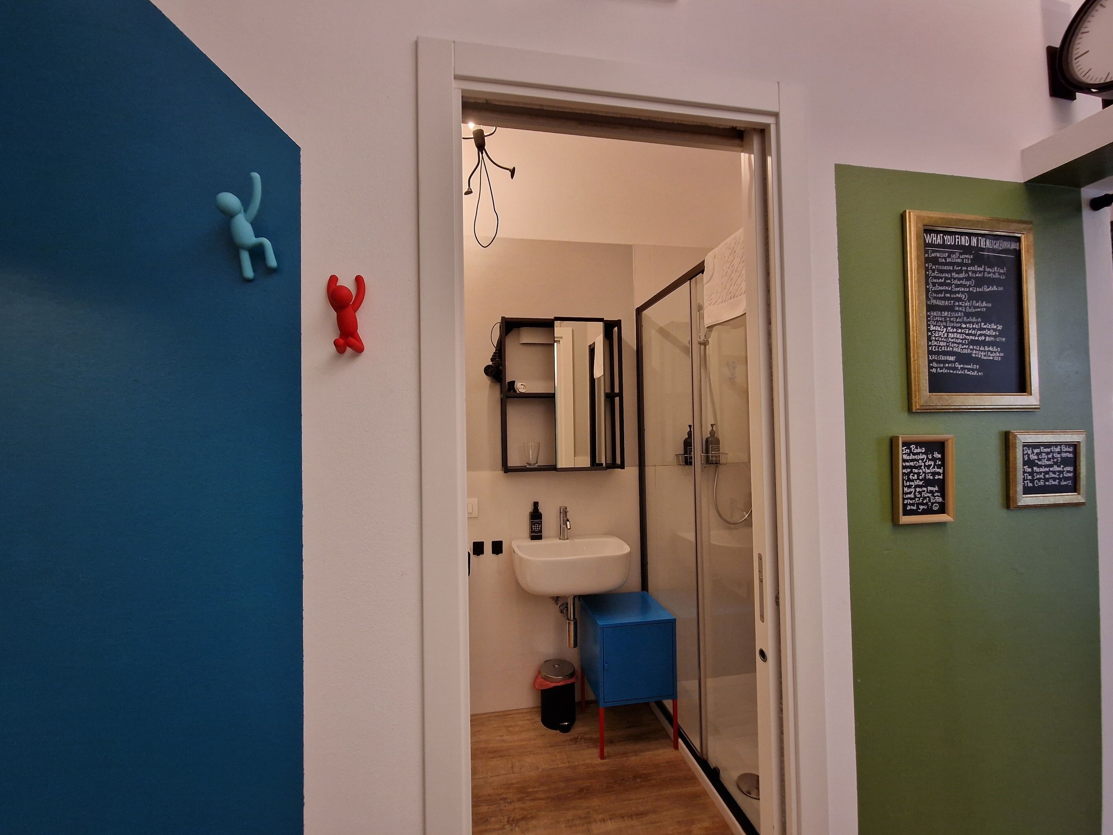 A modern bathroom with a glass shower enclosure, a white sink, and a blue cabinet.