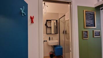 A modern bathroom with a glass shower enclosure, a white sink, and a blue cabinet.