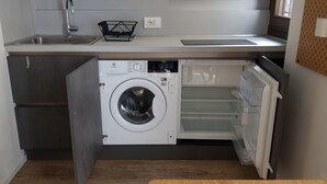 Cocina compacta con lavadora y secadora integradas, un lavamanos y una encimera.