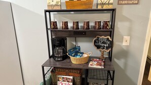 A shelf with a coffee maker, a basket of door hangers, a 'Picnic' cookbook, and a 'Life is Better in Grand Rapids' sign. - Riverside Hideaway, 880sf, 1 bedroom, 2nd story, apartment (Grand Rapids)