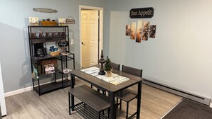 A dining area with a table, benches, a coffee machine, and a bookshelf. - Riverside Hideaway, 880sf, 1 bedroom, 2nd story, apartment (Grand Rapids)