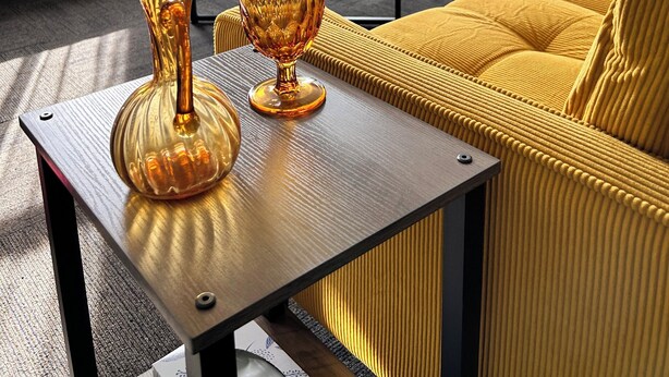 A modern living room with a yellow sofa, a blue armchair, and a coffee table with decorative glass vases. - Riverside Hideaway, 880sf, 1 bedroom, 2nd story, apartment (Grand Rapids)
