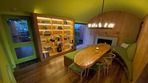 A cozy room with a wooden table and chairs, a bookshelf, and a fireplace.