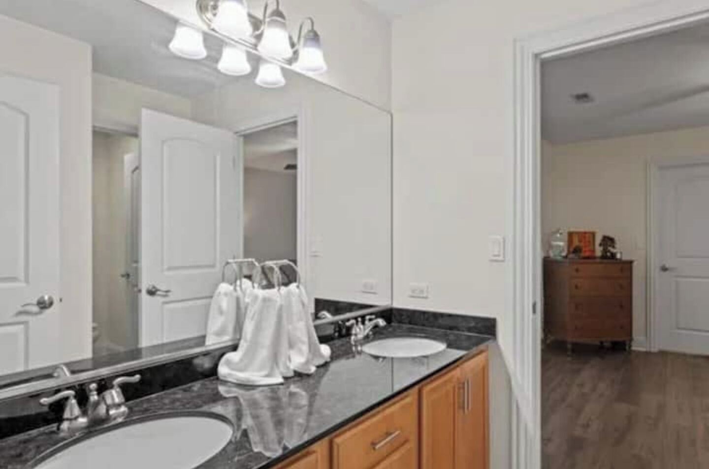 Un baño moderno con dos lavamanos, un espejo grande y un mueble de tocador con armarios.