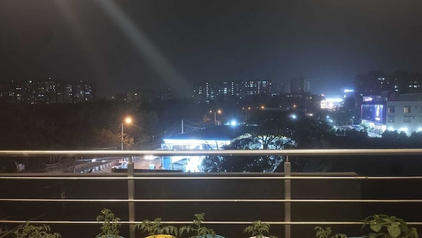 A night view from a balcony with potted plants in front of a cityscape. - Blue Rocks Suites, Sarjapur Road (Bengaluru)