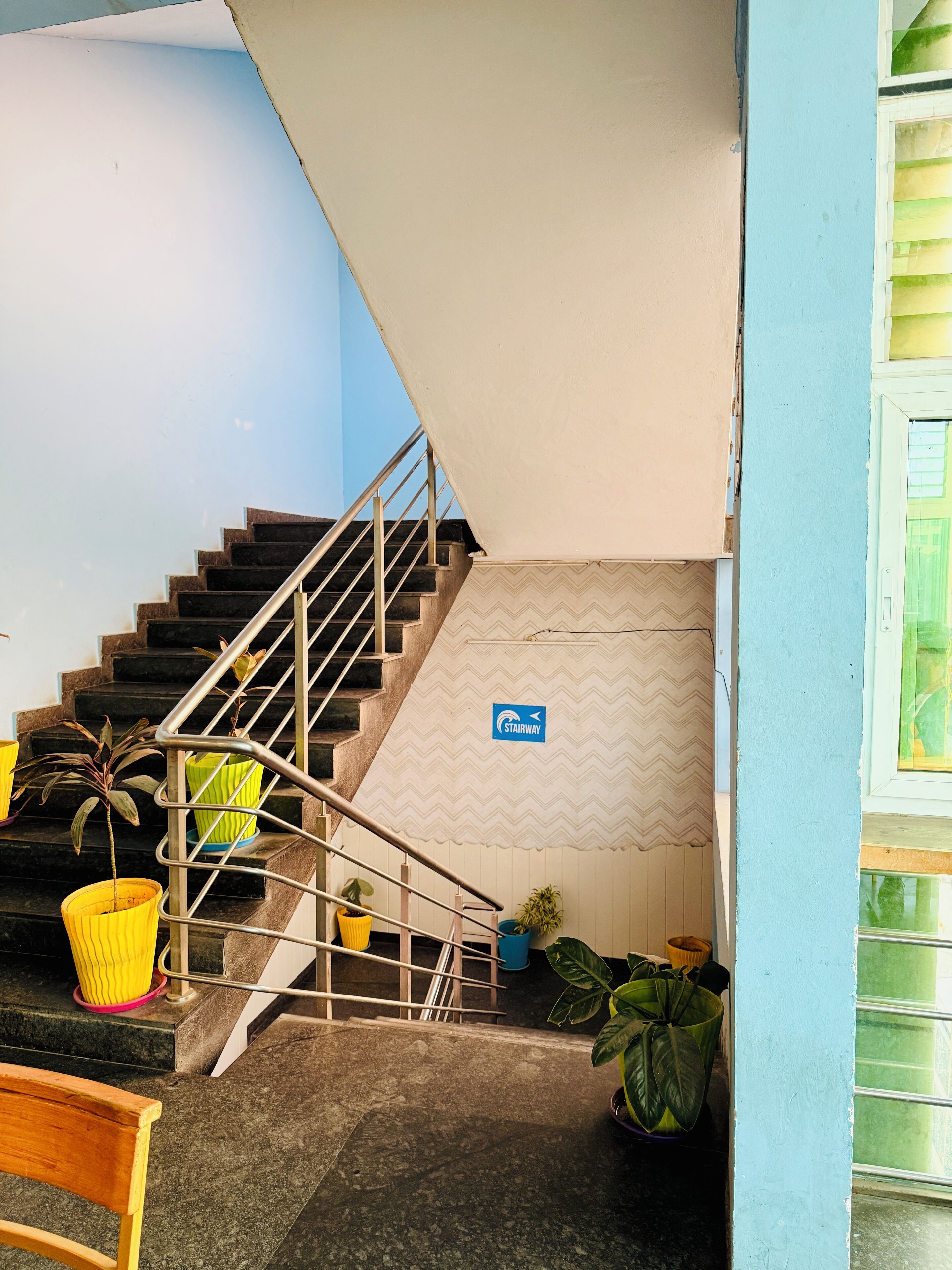 A staircase with a 'Stairway' sign, potted plants, and a wooden bench.