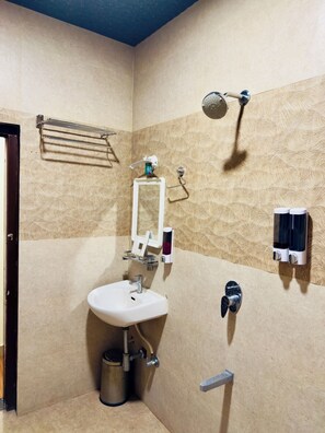 Un baño con lavamanos, toallero, ducha y dispensador de jabón.