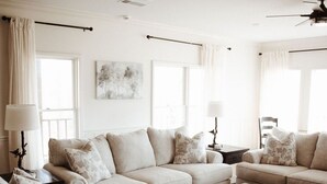 Ein Wohnzimmer mit einer Couch, Sesseln, einem Couchtisch und einem Deckenventilator.