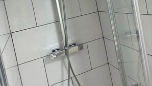 A shower with a glass enclosure, a handheld showerhead, and a wall-mounted control panel. - Newly Built Private Ensuite Room (Manchester)