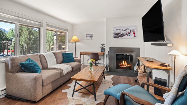 En stue med sofa, sofabord, fjernsyn, pejs og skrivebord.