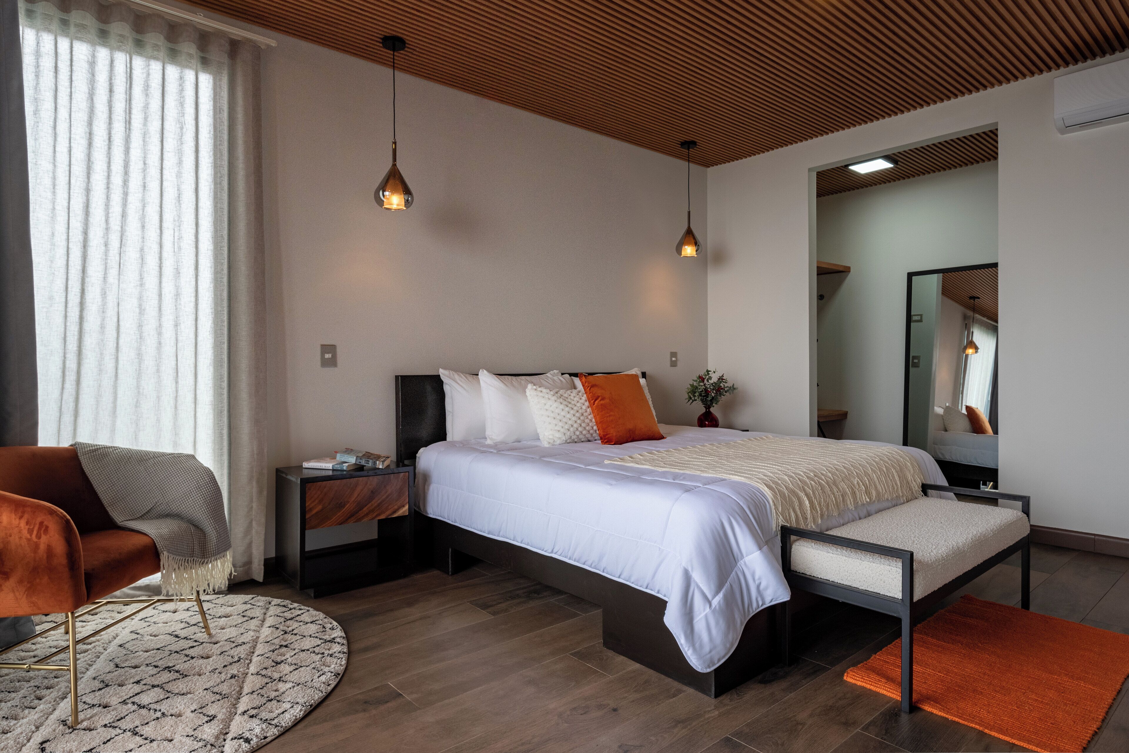 A modern bedroom with a large bed, a nightstand, a chair, and a round rug.