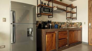 A kitchen with a stainless steel refrigerator, wooden cabinets, a microwave, and a coffee machine.