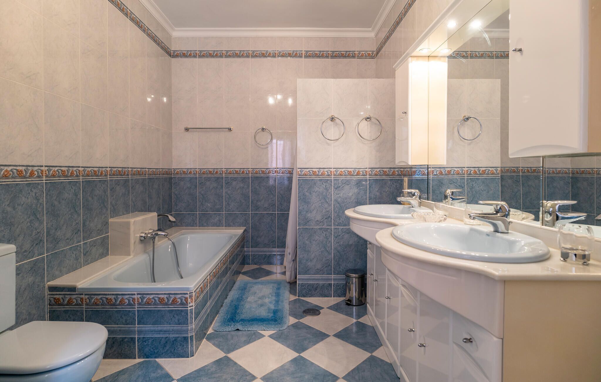Un bagno con vasca, due lavabi, un water e una doccia.