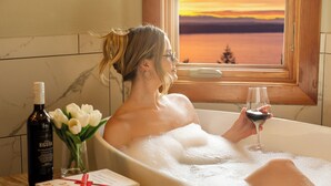 En person slapper af i et badekar med udsigt til en solnedgang gennem et vindue, en flaske vin og en bog med titlen "Secure Love" på et sengebord.