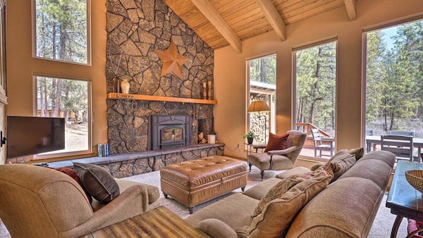 A cozy living room with a stone fireplace, large windows, and comfortable seating. - 5BR. Hot Tub! Full resort access (Sisters)