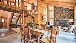 A rustic wooden interior with a dining area, fireplace, and a staircase leading to an upper level. - 5BR. Hot Tub! Full resort access (Sisters)