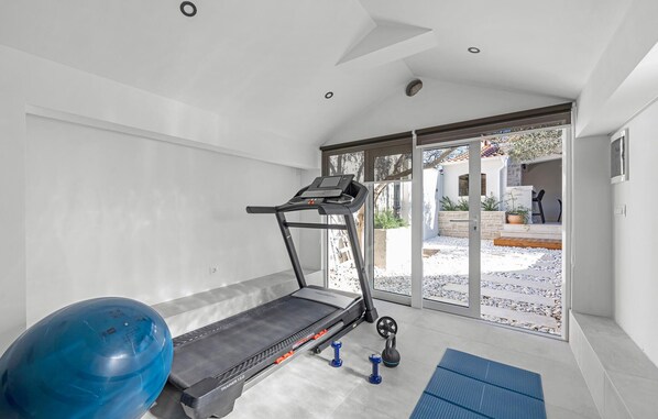 A home gym with a treadmill, exercise balls, and weights.