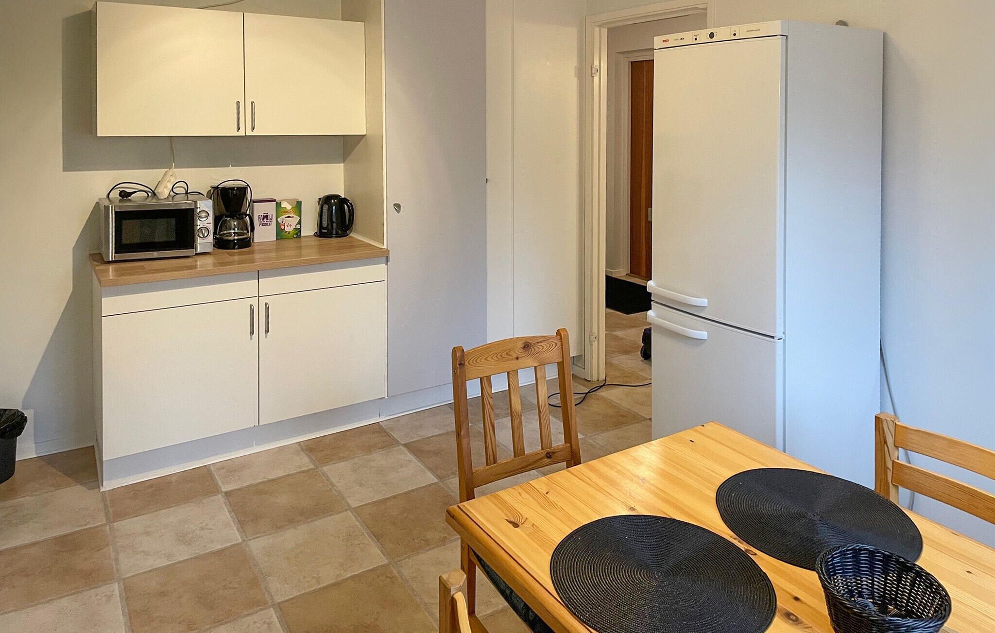 A compact kitchen with white cabinets, a microwave, a coffee maker, and a refrigerator.