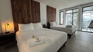 Een hotelkamer met twee bedden, houten paneel hoofdbord, een nachtkastje met een lamp, en een groot raam met uitzicht op bomen.