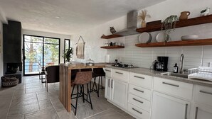 Een moderne keuken met witte kasten, een houten eiland en een groot raam met uitzicht op een prachtig landschap.