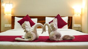 Een hotelkamer met een bed, versierd met twee zwanenhanddoeken en rode kussens.