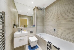 A modern bathroom with a glass-enclosed shower, a white sink, and a bathtub. - Second nest Brixton (London)