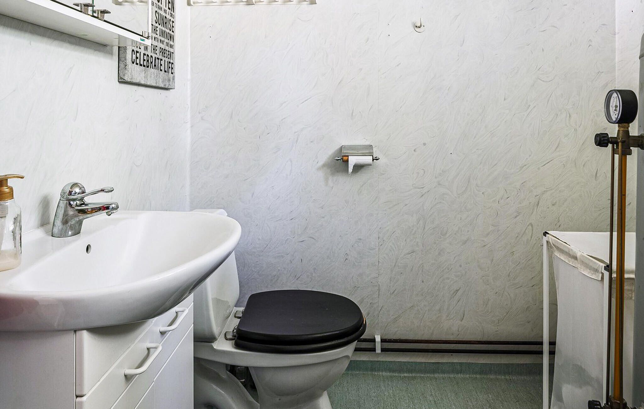 A small bathroom with a white sink, a toilet, and a toilet paper holder on the wall.