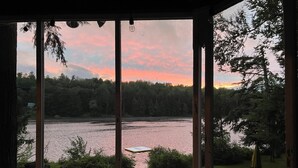 Eine Terrassennische am Seeufer mit Gartenmöbeln und Blick auf See und Wald.