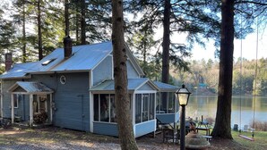 Eine Hütte mit überdachter Veranda, einer kleinen Terrasse und Seeblick.