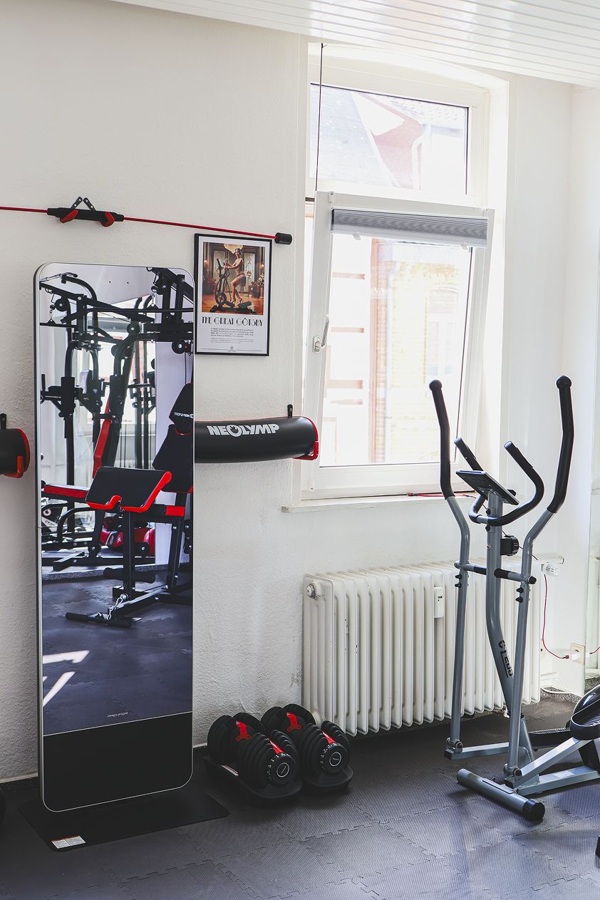 A gym with exercise equipment, a window, and a radiator.
