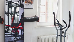 A gym with exercise equipment, a window, and a radiator.