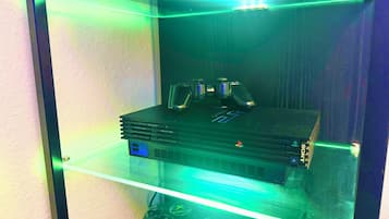 Ein Gaming-Einrichtung mit einer PS4, einem Controller und einem Monitor in einer Vitrine.