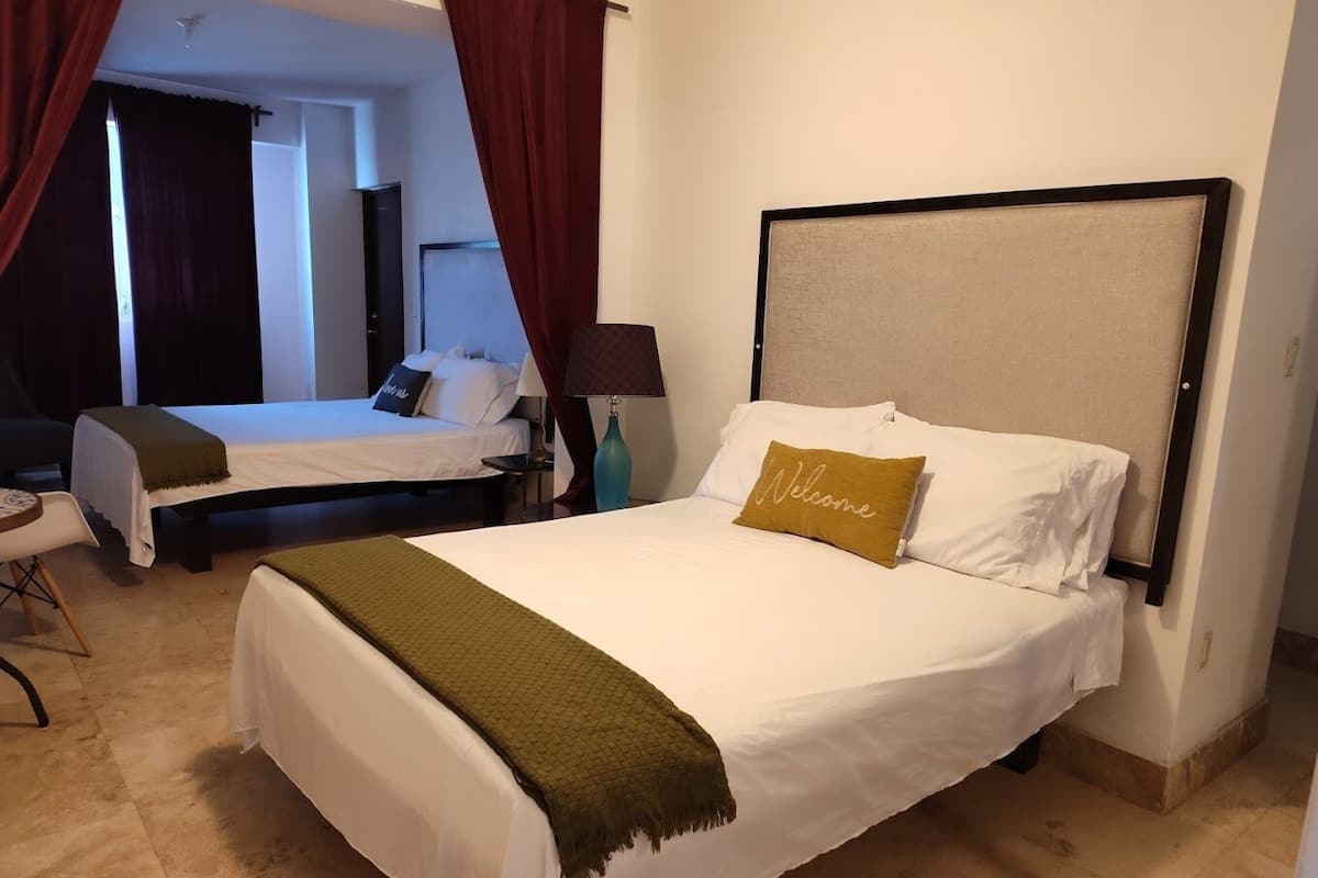 Quarto de hotel com duas camas, uma escrivaninha e uma cadeira.