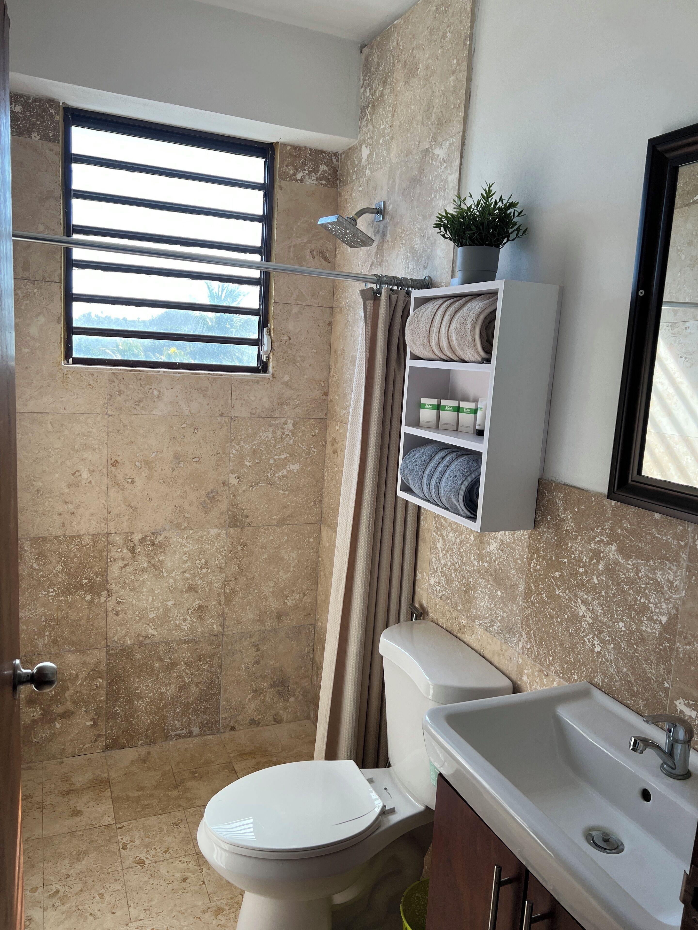 Une salle de bain avec douche, toilettes et lavabo.