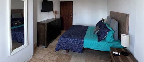 Una camera da letto con un letto, una televisione, una scrivania e una sedia.