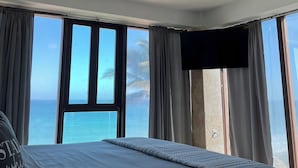 Un dormitorio con una cama, un ventilador de techo y un gran ventanal con vistas al océano.