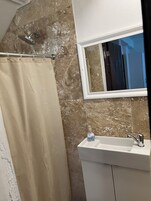 A bathroom with a shower, a sink, and a mirror.