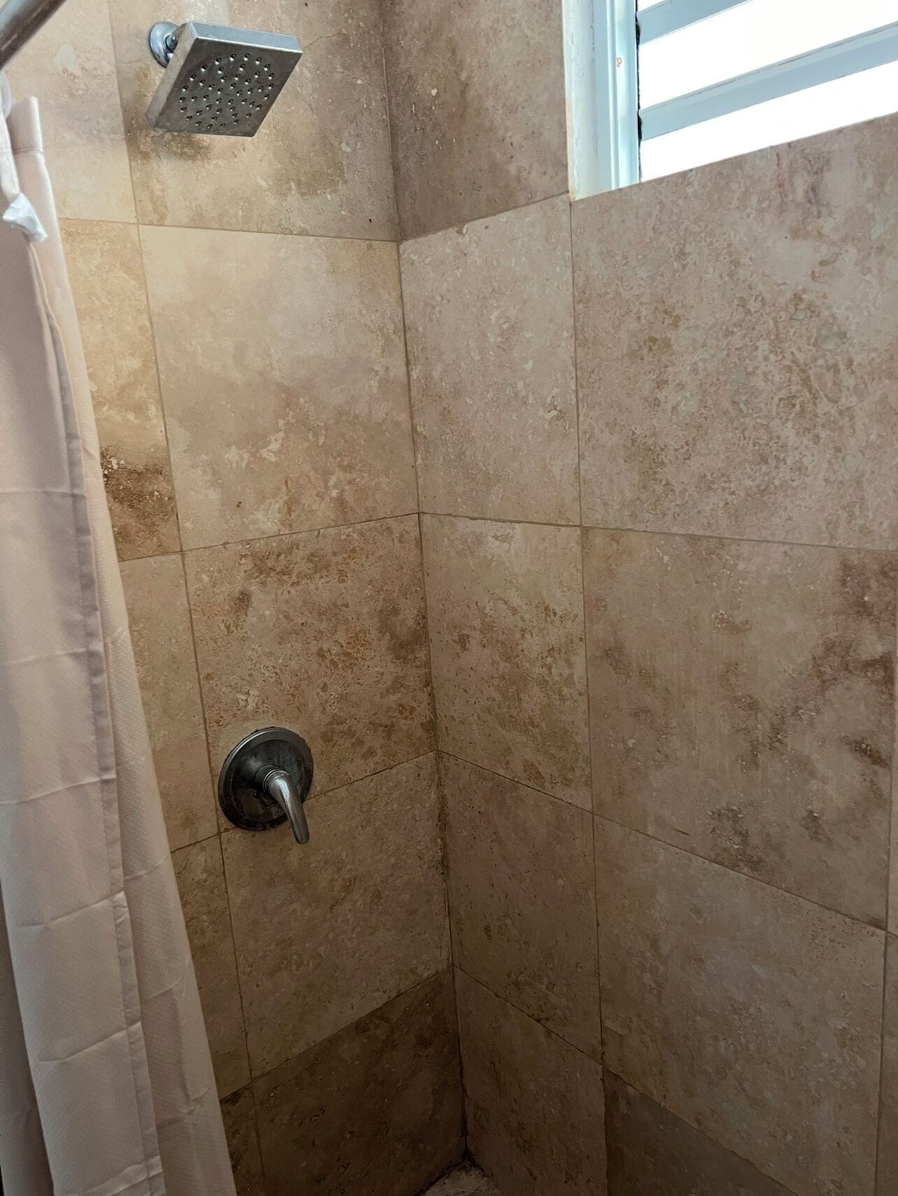 Zona de ducha con azulejos color beige y ducha.