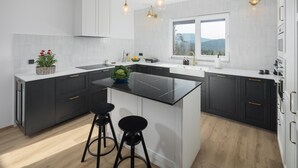 A modern kitchen with dark cabinetry, a central island, and bar stools.
