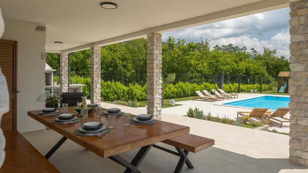 An outdoor dining area with a pool and lounge chairs.