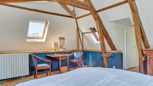 A bedroom with a sloped ceiling, a skylight, a bed, a desk, and a chair.