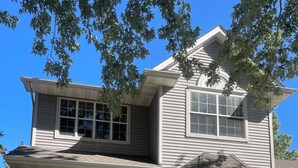 A two-story house with a front porch, a garage, and a large window. - Pondhaven Rereat Fully furnished house with fun and convenience for all ages (Farmington)
