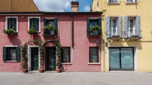 A pink building with green shutters and potted plants. - Historic housing in pedestrian square - Borgo Portello (Padova)