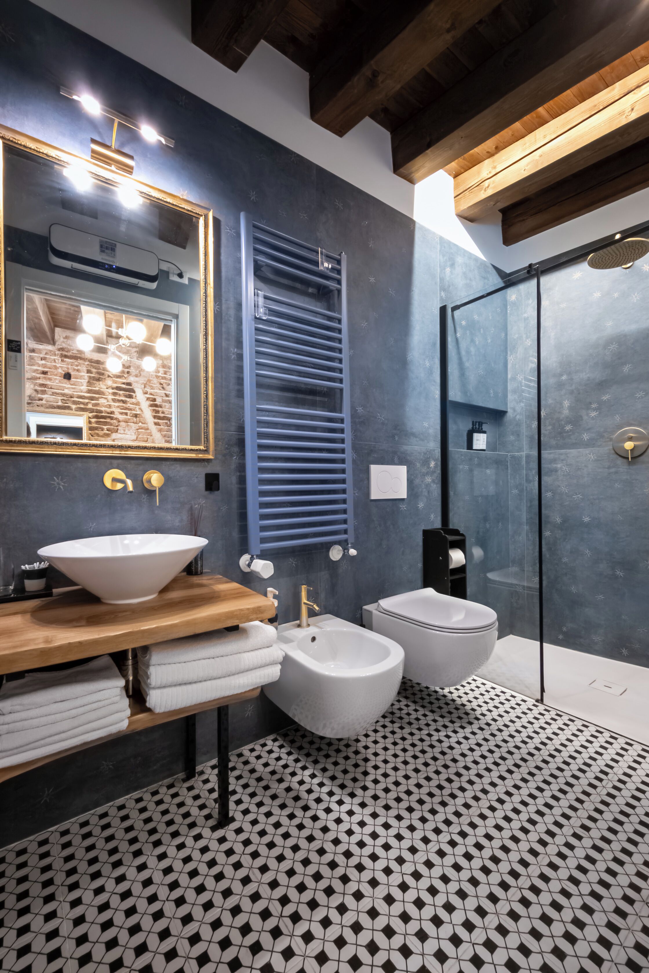 Un baño moderno con un espejo grande, lavamanos blanco y zona de ducha.