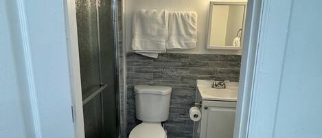 A compact bathroom with a toilet, sink, and shower.