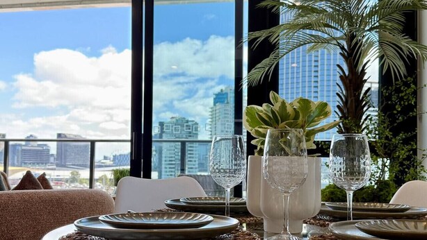 Mesa de jantar posta para quatro com vista desimpedida da linha do horizonte da cidade através de grandes janelas.